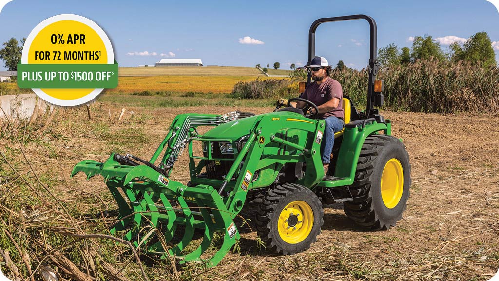 0% APR for 72 months, plus up to 1500 dollars off advertisement showing a man in the seat of a John Deere 3E tractor with grapple moving brush.